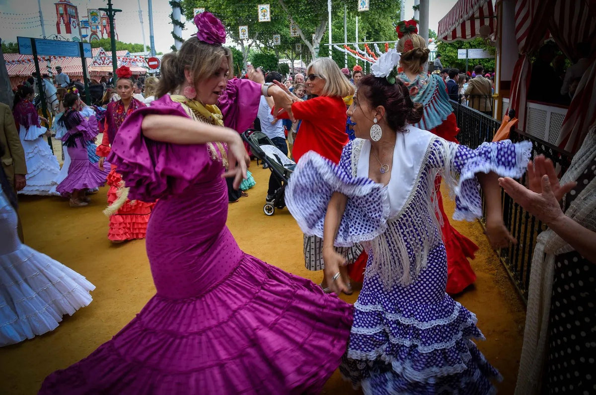 Mujeres vestidas de flamenca bailando sevillanas en el Real de la Feria