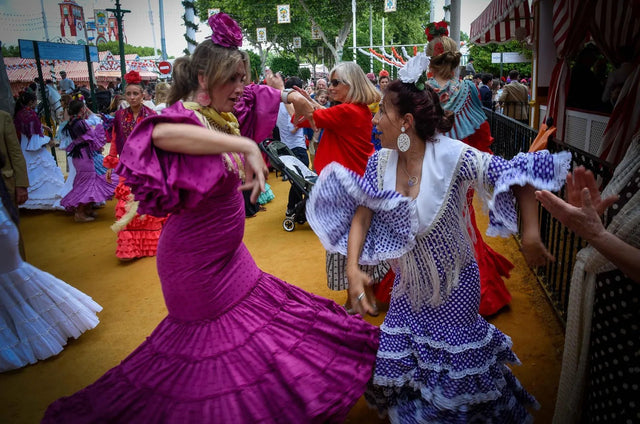 Mujeres vestidas de flamenca bailando sevillanas en el Real de la Feria